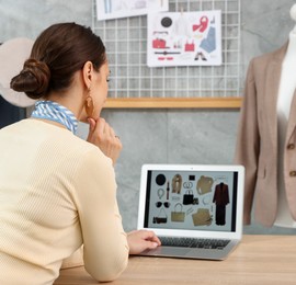 Photo of Professional stylist with picture of outfit on laptop at desk indoors