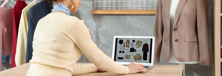 Photo of Professional stylist with picture of outfit on laptop at desk indoors
