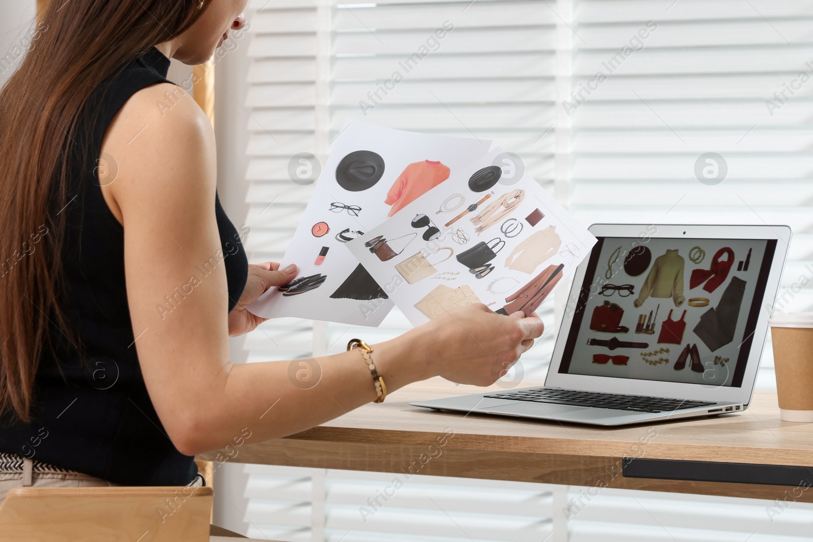 Professional stylist making collage with outfit on laptop at desk indoors Photo of Professional stylist making collage with outfit on laptop at desk indoors