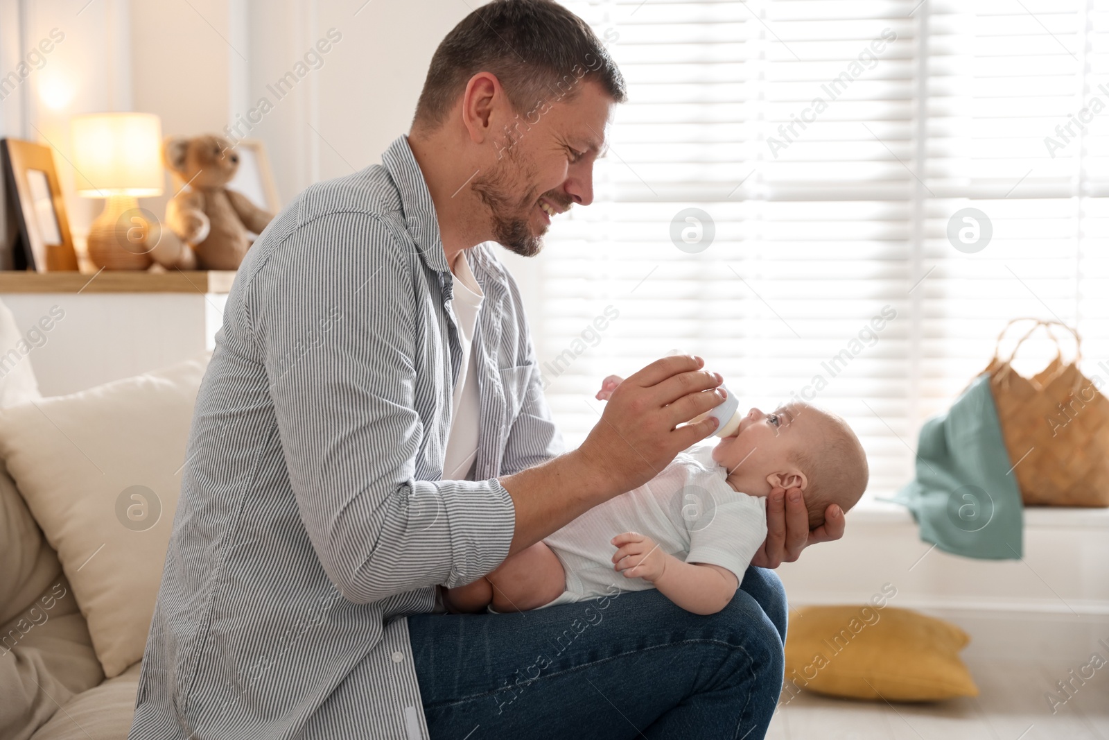 Father feeding his little baby with bottle on sofa at home Photo of Father feeding his little baby with bottle on sofa at home