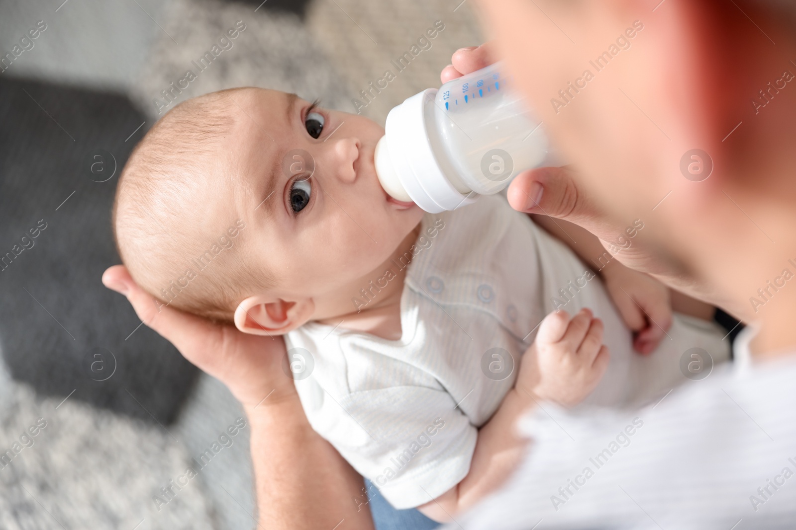Father feeding his little baby with bottle at home, closeup Photo of Father feeding his little baby with bottle at home, closeup