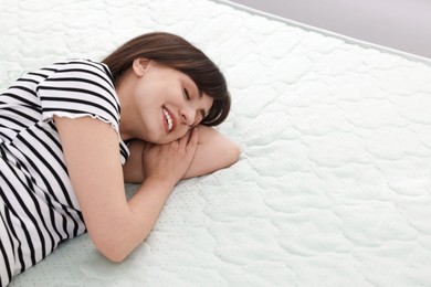 Photo of Beautiful woman sleeping on soft mattress at home, space for text
