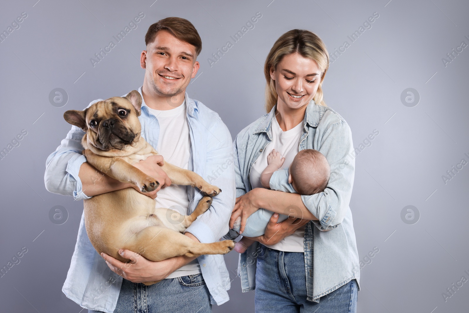 Happy family with little baby and cute dog on grey background Photo of Happy family with little baby and cute dog on grey background