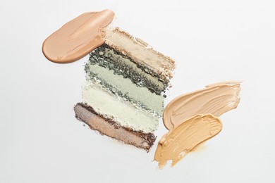 Photo of Colorful eyeshadows and foundation on white background, flat lay