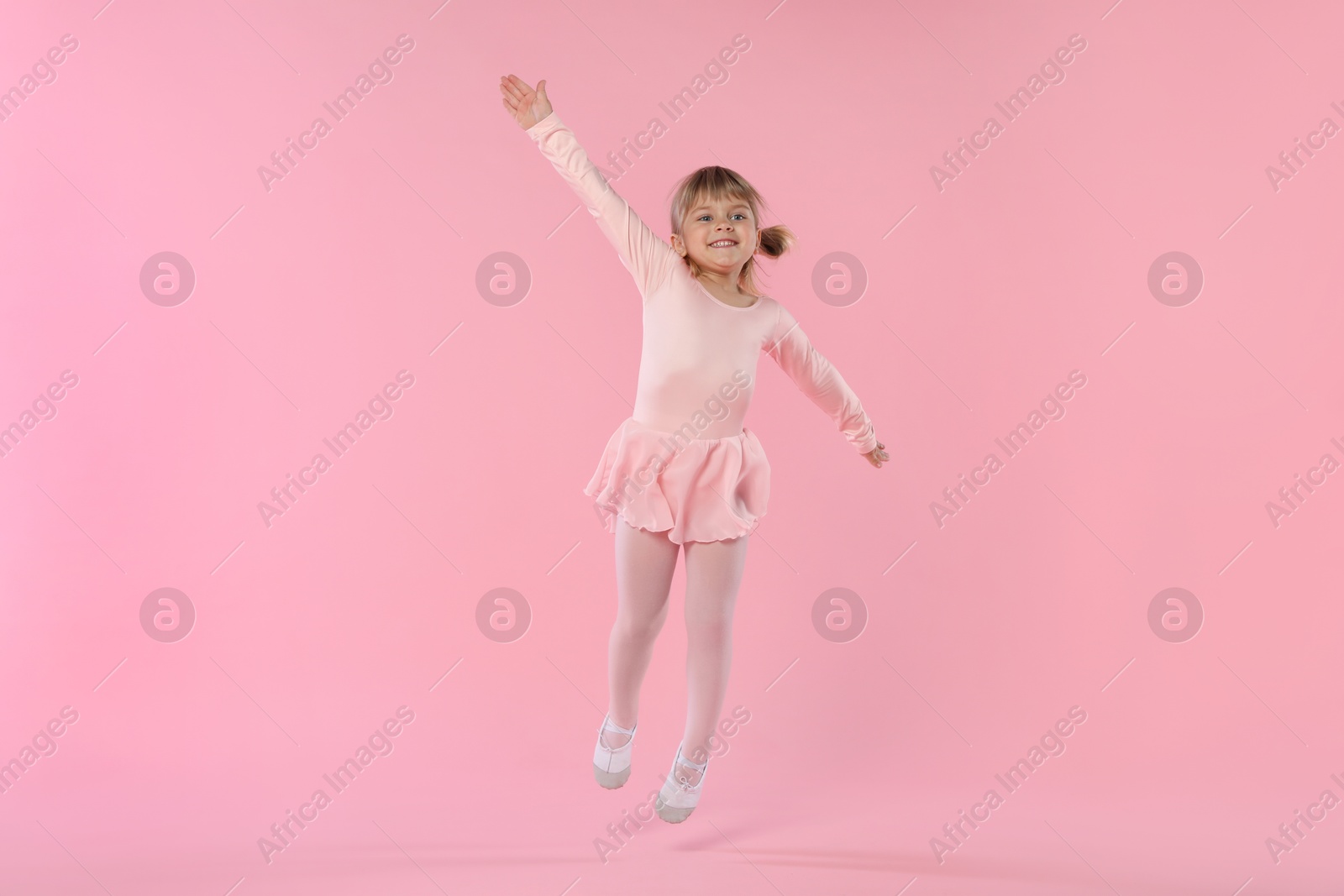 Cute little girl dancing on pink background Photo of Cute little girl dancing on pink background