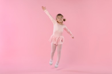 Photo of Cute little girl dancing on pink background