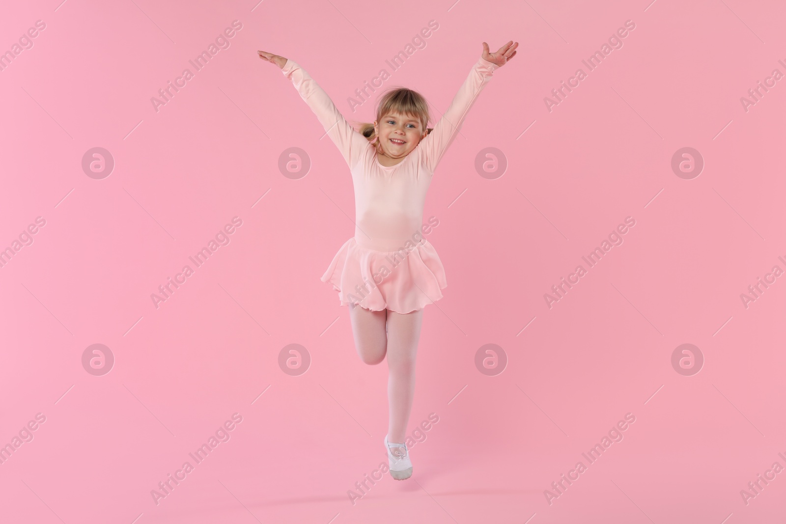 Cute little girl dancing on pink background Photo of Cute little girl dancing on pink background