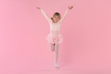 Photo of Cute little girl dancing on pink background