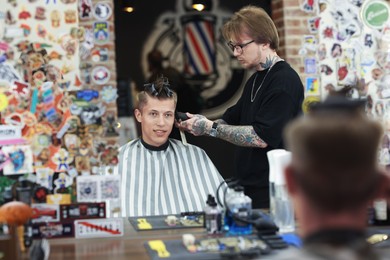 Photo of Professional barber making stylish haircut in barbershop