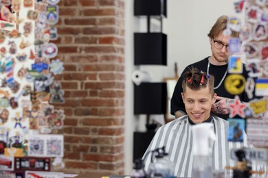 Photo of Professional barber making stylish haircut in barbershop