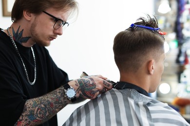 Photo of Professional barber making stylish haircut in barbershop
