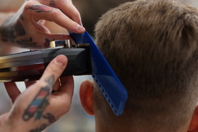 Photo of Professional barber making stylish haircut in barbershop, closeup