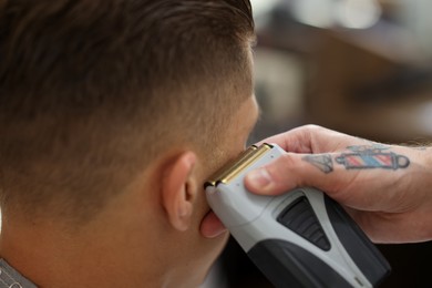 Photo of Professional barber working with client in barbershop, closeup