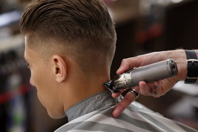 Photo of Professional barber working with client in barbershop, closeup