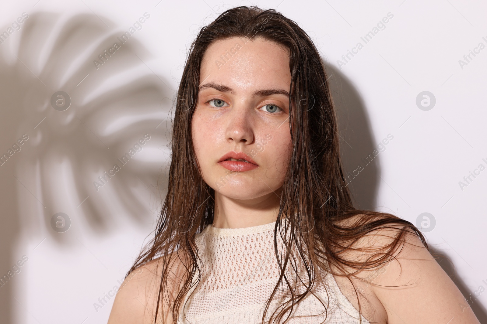 Portrait of beautiful woman with natural skin complexion on light background with shadows, closeup Photo of Portrait of beautiful woman with natural skin complexion on light background with shadows, closeup