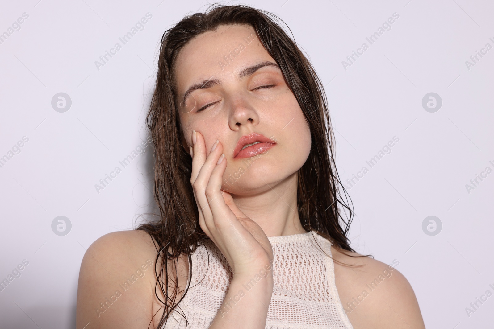 Beautiful woman with natural skin complexion on light grey background, closeup Photo of Beautiful woman with natural skin complexion on light grey background, closeup