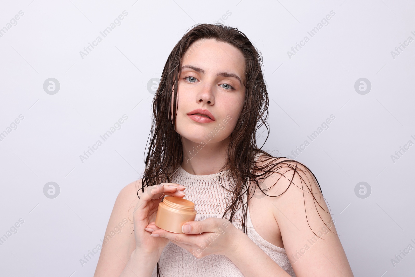 Portrait of beautiful woman with jar of skincare product on light grey background, closeup Photo of Portrait of beautiful woman with jar of skincare product on light grey background, closeup