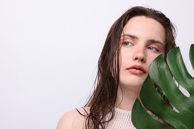 Photo of Portrait of beautiful woman with natural skin complexion and monstera leaf on grey background, closeup. Space for text
