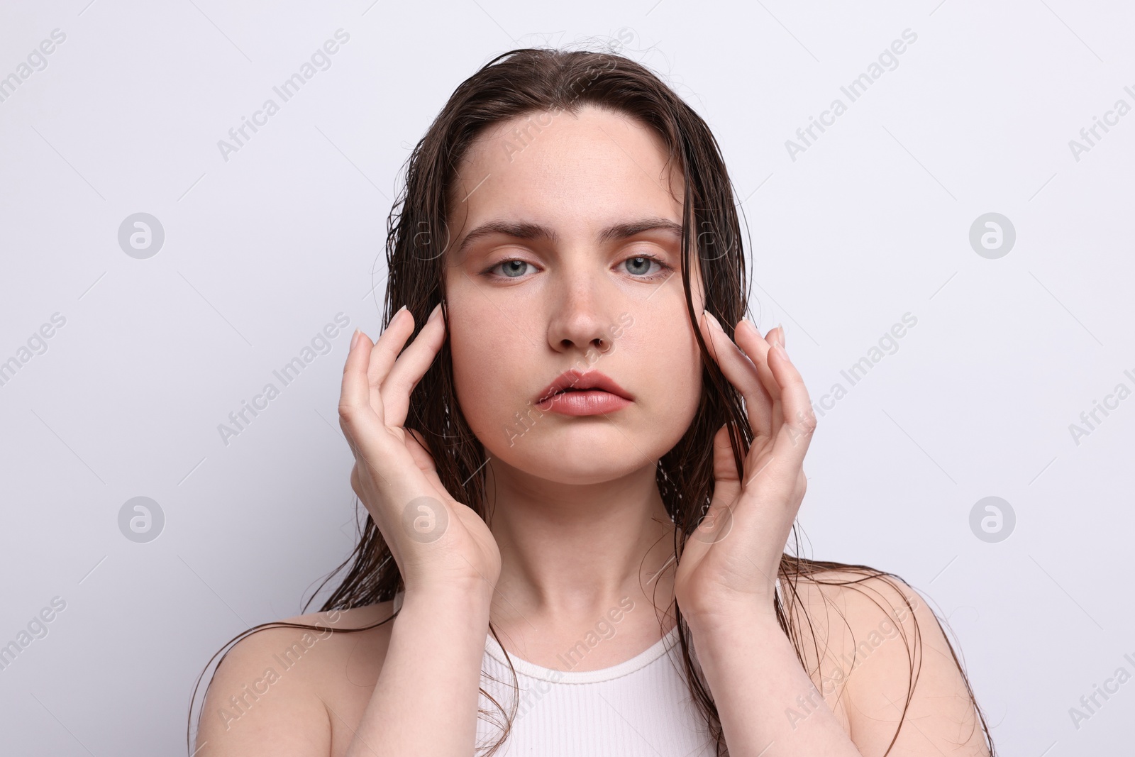 Portrait of beautiful woman with natural skin complexion on light grey background, closeup Photo of Portrait of beautiful woman with natural skin complexion on light grey background, closeup