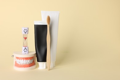 Photo of Different oral care products and dental model on beige background. Space for text