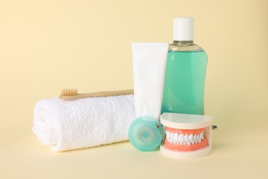 Photo of Different oral care products and dental model on beige background