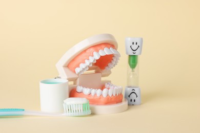 Photo of Different oral care products and dental model on beige background, closeup