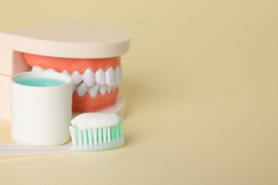 Photo of Different oral care products and dental model on beige background, closeup. Space for text