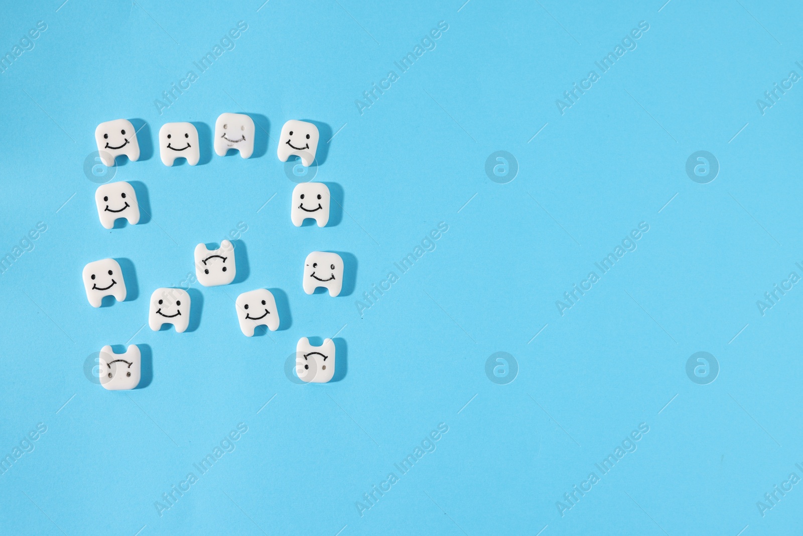 Tooth made with small teeth figures on light blue background, flat lay. Space for text Photo of Tooth made with small teeth figures on light blue background, flat lay. Space for text
