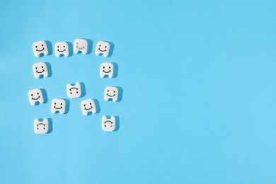 Photo of Tooth made with small teeth figures on light blue background, flat lay. Space for text