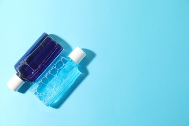 Photo of Bottles of mouthwash on light blue background, top view. Space for text