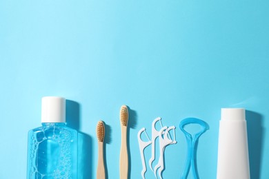 Photo of Different oral care products on light blue background, flat lay. Space for text