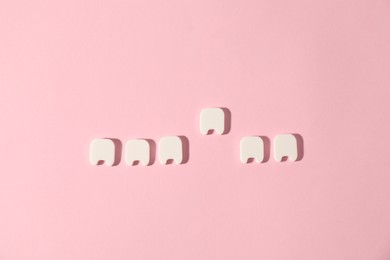 Photo of Small teeth figures on pink background, flat lay