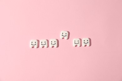 Photo of Small teeth figures on pink background, flat lay
