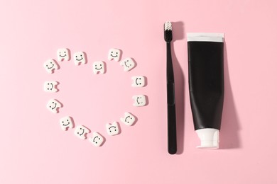 Photo of Heart made with teeth figures, toothbrush and paste on pink background, flat lay