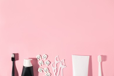 Photo of Different oral care products and teeth figures on pink background, flat lay. Space for text