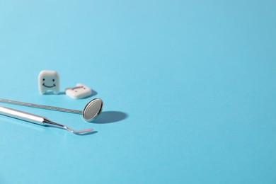 Photo of Dentist's tools and teeth figures on light blue background, closeup. Space for text