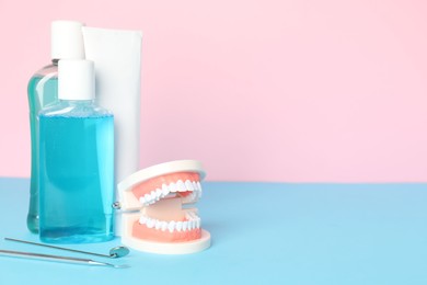 Photo of Different oral care products and dental model on color background. Space for text