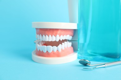Photo of Different oral care products and dental model on light blue background, closeup