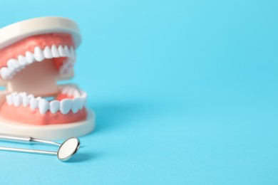 Photo of Dental model and tools on light blue background, closeup. Space for text