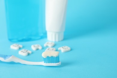 Photo of Different oral care products and teeth figures on light blue background, closeup