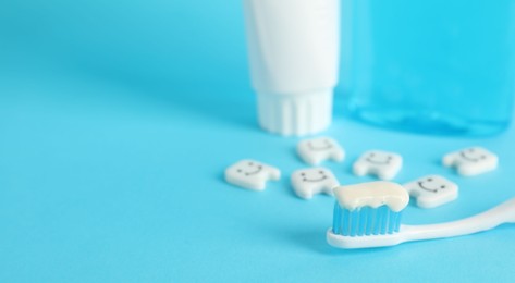 Photo of Different oral care products and teeth figures on light blue background, closeup. Space for text