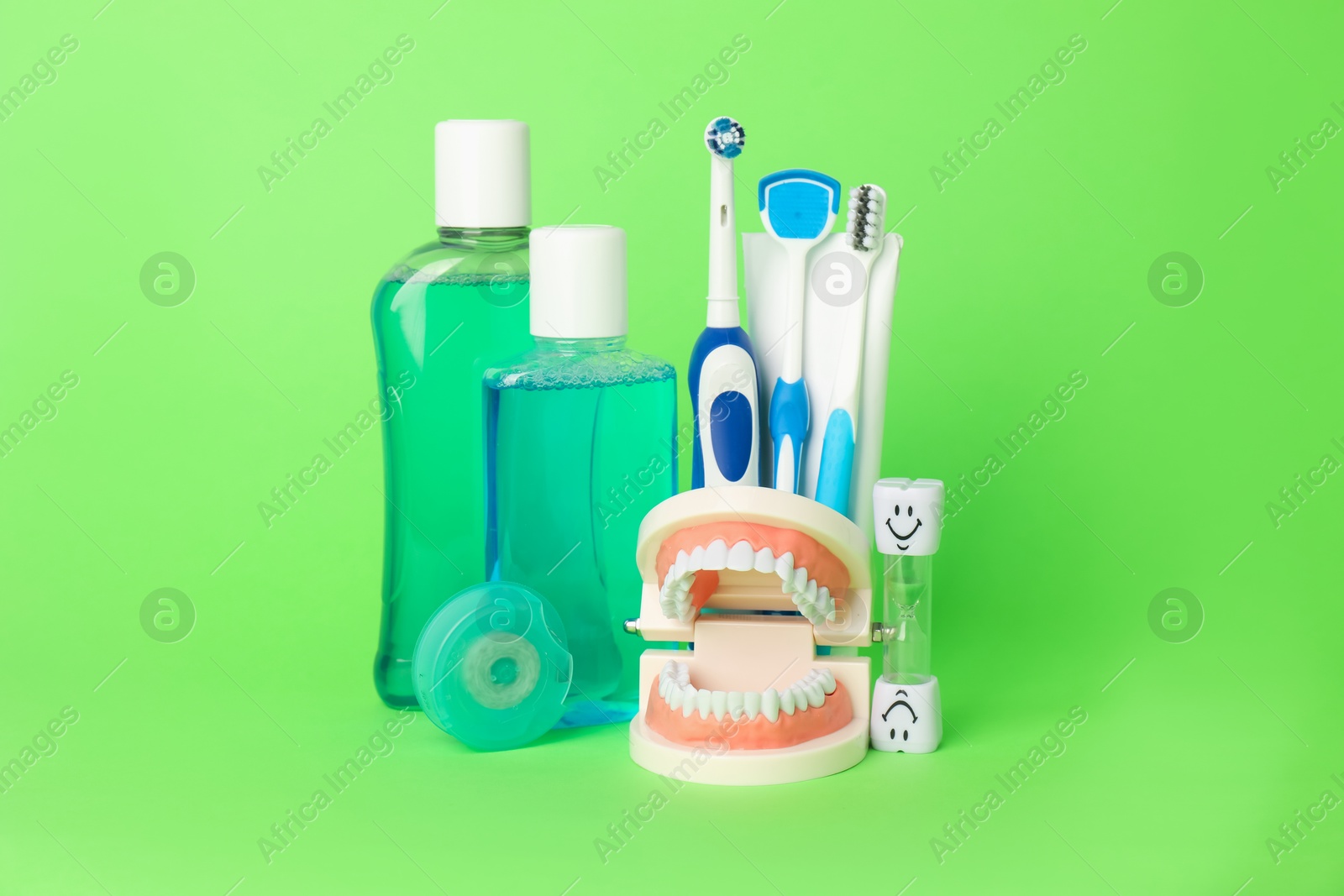 Different oral care products and dental model on green background Photo of Different oral care products and dental model on green background