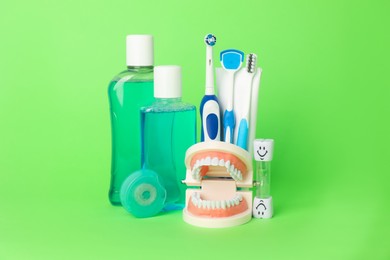 Photo of Different oral care products and dental model on green background