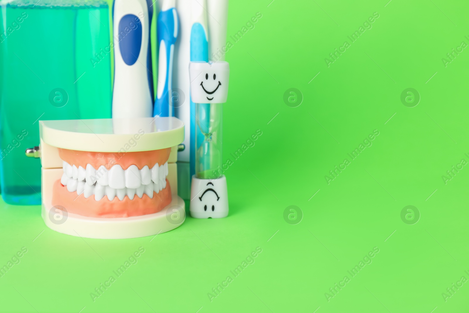 Different oral care products and dental model on green background, closeup. Space for text Photo of Different oral care products and dental model on green background, closeup. Space for text