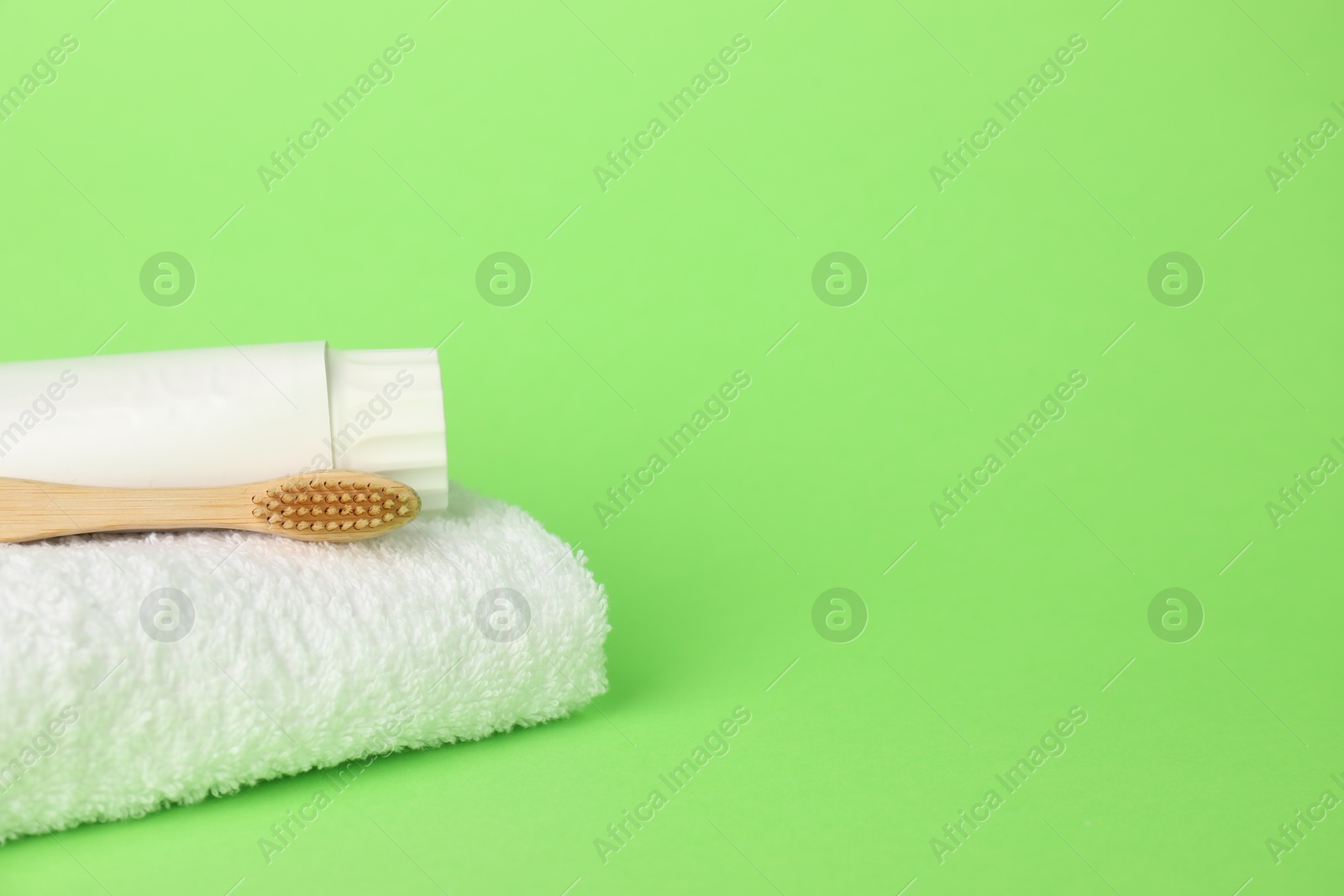 Towel with toothbrush and paste on green background, closeup. Space for text Photo of Towel with toothbrush and paste on green background, closeup. Space for text