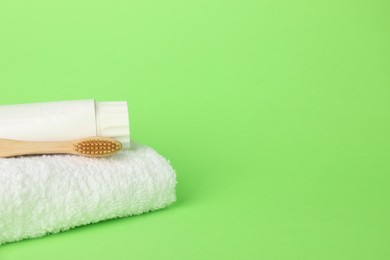 Photo of Towel with toothbrush and paste on green background, closeup. Space for text
