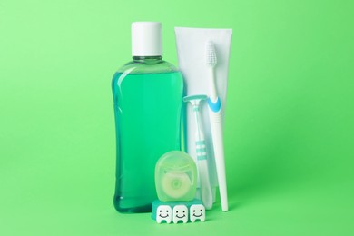 Photo of Different oral care products and teeth figures on green background