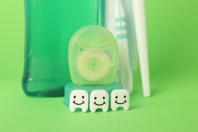 Photo of Different oral care products and teeth figures on green background, closeup