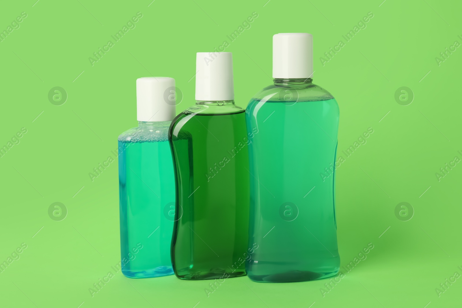 Different bottles of mouthwash on green background Photo of Different bottles of mouthwash on green background