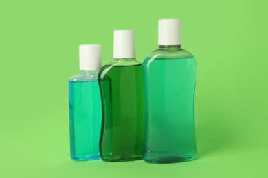 Photo of Different bottles of mouthwash on green background